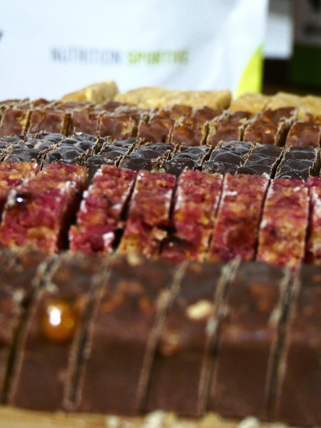 Barres protéinées de différentes saveurs : fruits rouges, citron meringué, cacao, noix de coco et cookie and cream, coupées sur un plateau, de la marque 1Defy Nutrition Sportive Made in Bourgogne