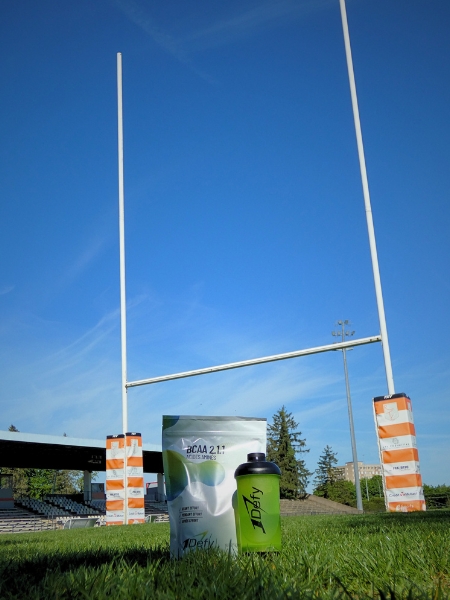 BCAA 2.1.1 saveur passion et son shaker devant des poteaux de rugby - 1Defy Nutrition Sportive Made in Bourgogne