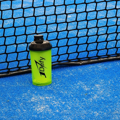 Shaker 1Defy nutrition sportive made in bourgogne, sur un terrain de padel, devant le filet