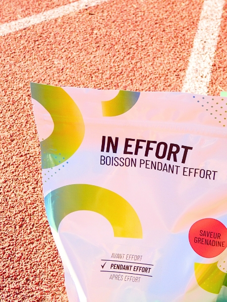 Sachet de boisson isotonique In Effort saveur grenadine sur une piste d'athlétisme de la marque 1Defy Nutrition Sportive, made in bourgogne