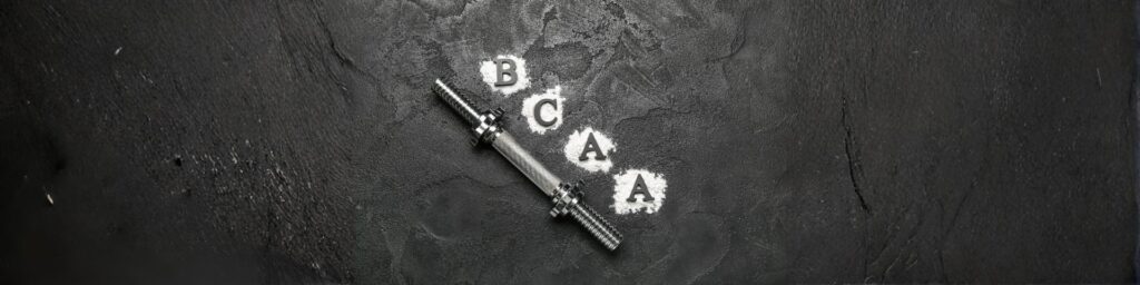 Image descriptive de l'article de blog : BCAA : rôle et bienfaits pour la croissance musculaire Image représentant une barre de musculation avec une inscription BCAA dans de la poudre à côté